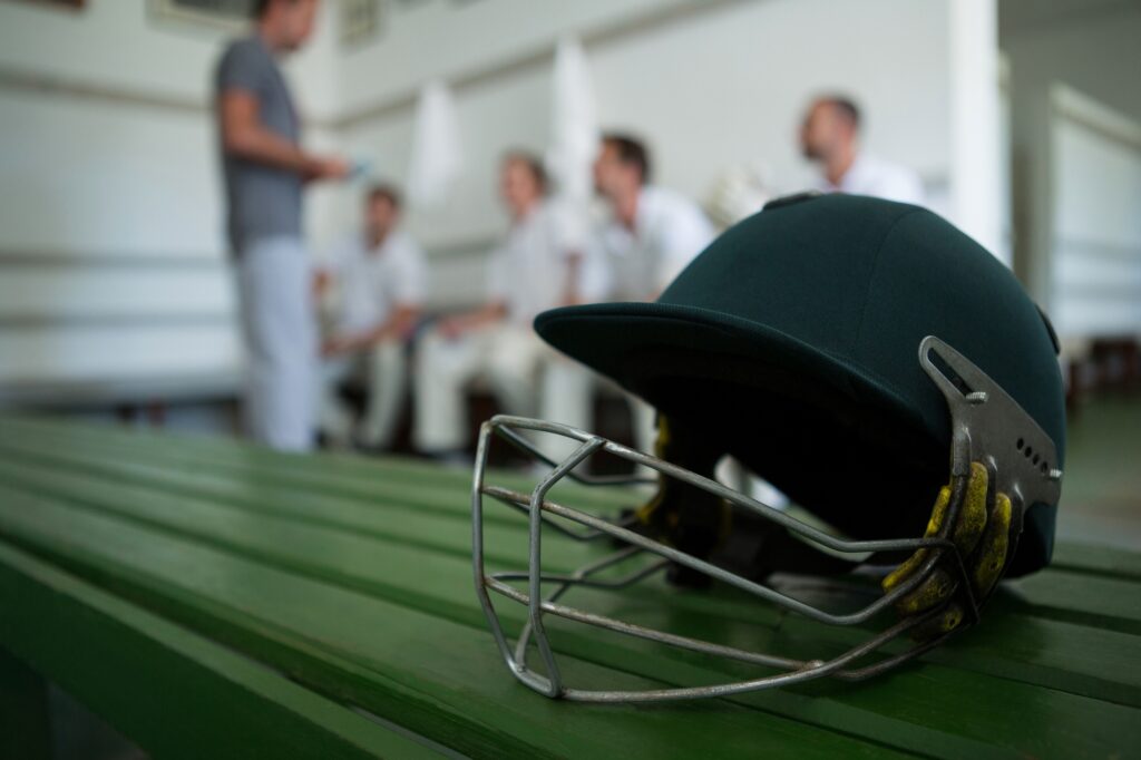 Close up of cricket helmet on table against team